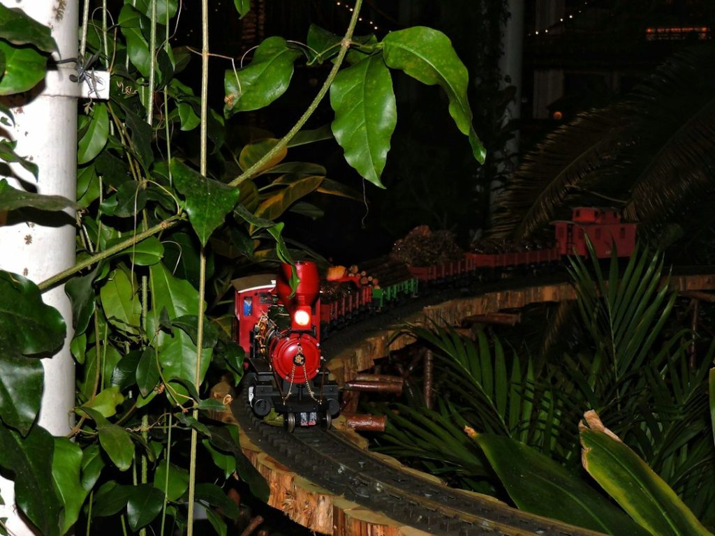 A miniature train travelling through a landscaped model scene