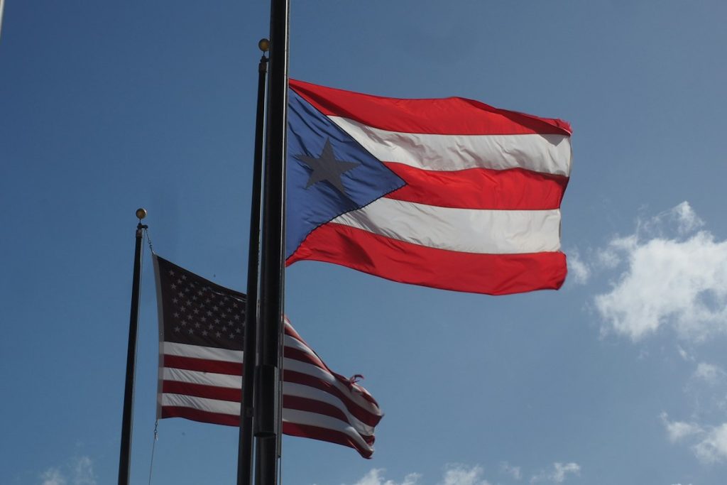 Two flags flying side by side against a blue sky, representing identity and belonging