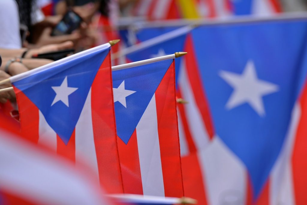 People carrying Puerto Rican flags at a public celebration, illustrating year-round community connections